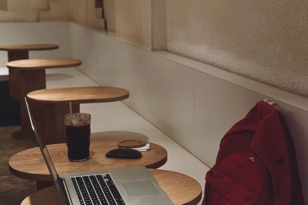 Cafe table with a laptop, a drink and a red backpack