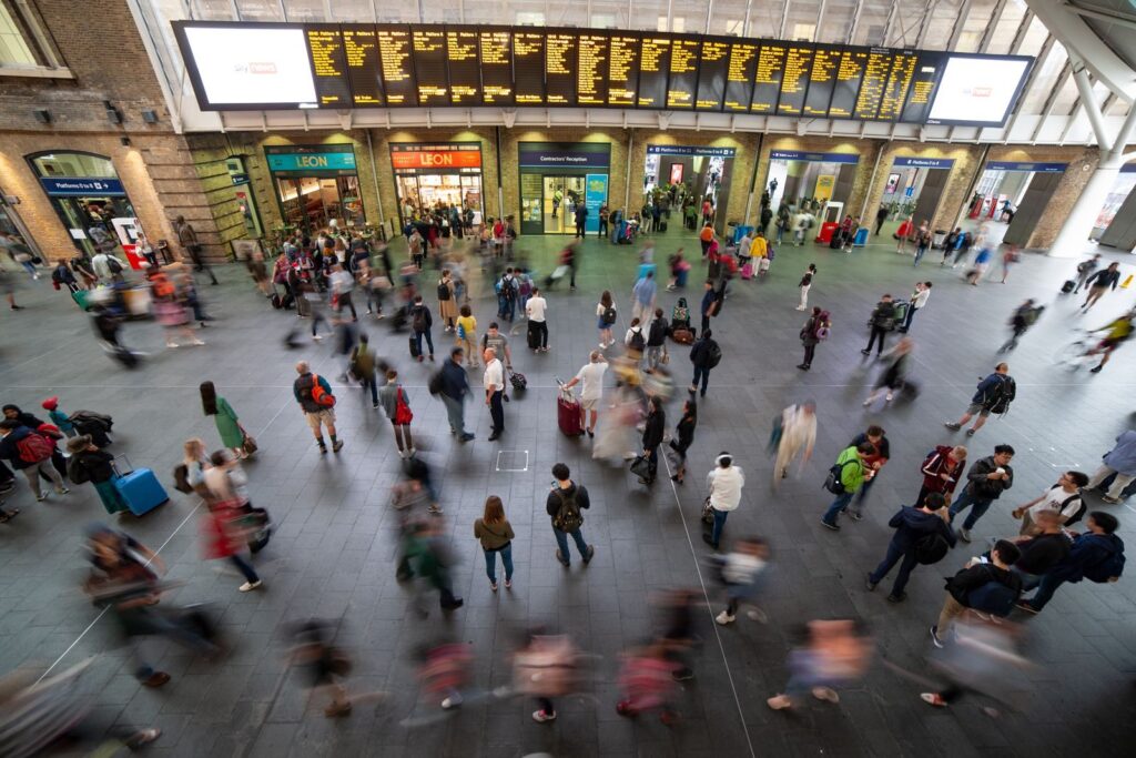 Busy railway station concourse seen from above, under departure boards