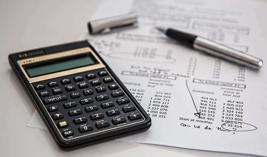 Black calculator and silver pen on a printed sheet of figures, for the OpenAI London salary breakdown