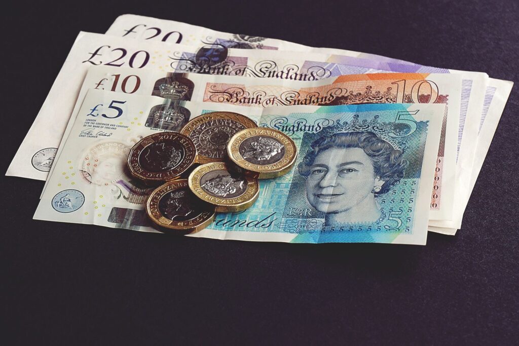 British pound notes with coins on a dark table, for the OpenAI London salary story