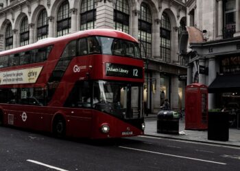 Red double-decker bus on a London street lined with stone buildings, for the OpenAI London salary story