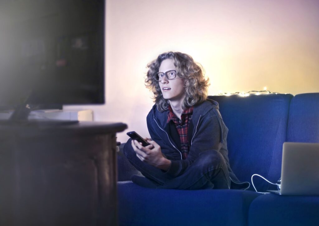 Fan on a sofa with a phone, ready to follow Rugby League World Cup 2026 on TV