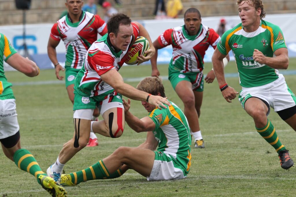 Rugby player running with the ball as opponents close in